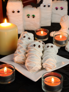 Nutter Butter Mummies are displayed on a table surrounded by lit orange candles.