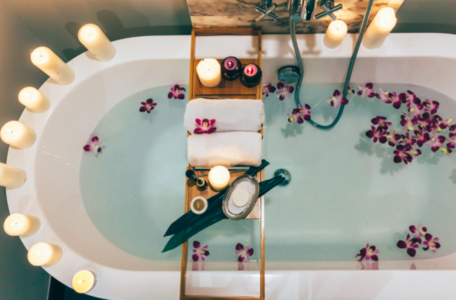 Overhead view of a bathtub with lit candles and flower petals