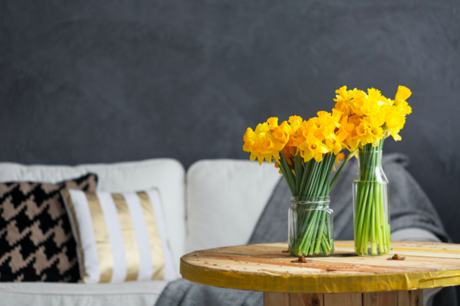 Yellow daffodils in a vase on a wooden table add yellow accents to a home.